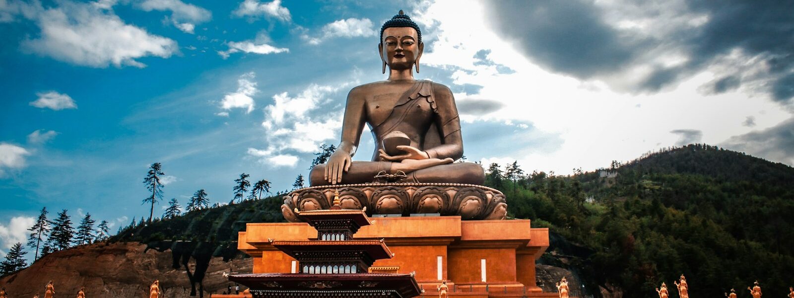 a statue of a man sitting on a throne in front of a building