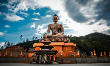 a statue of a man sitting on a throne in front of a building