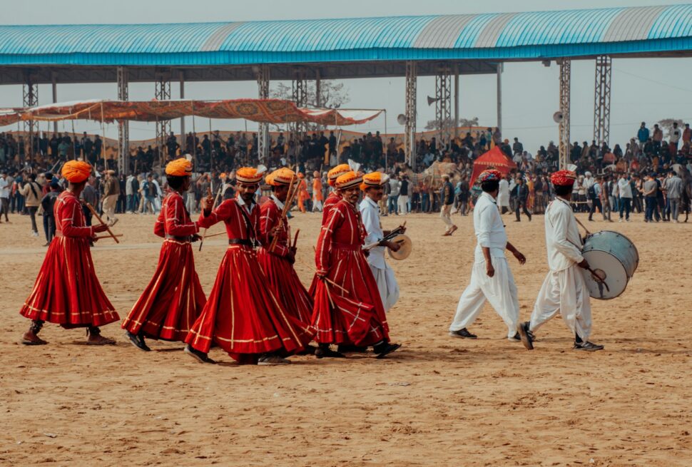 a group of people walking across a dirt field