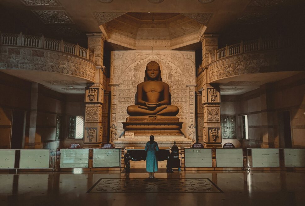 two people standing in front of a buddha statue